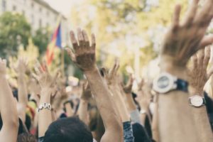Close up photos of people with hands in the air in the middle of a protest Human Rights