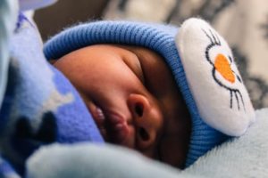 Close up photo of new born baby with a cute blue hat UNICEF