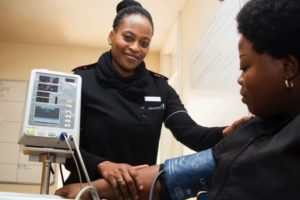 Lady smilling taking blood pressure of another lady GHDx